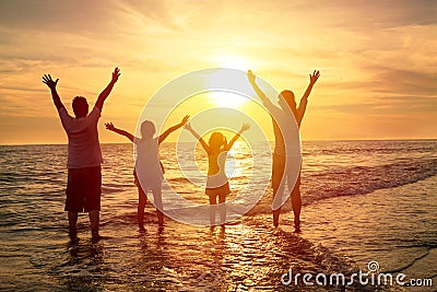 Happy family watching the sunset on the beach Stock Photo