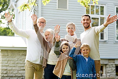 Happy family waving hands in front of house Stock Photo