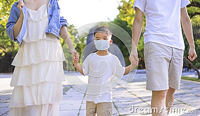 Happy family wearing the medical mask and walking in the park Stock Photo