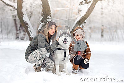 Happy family in the winter park plays about Huskies. Stock Photo