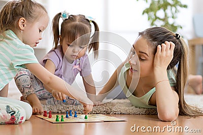 Happy family. Young mother playing ludo boardgame with her daughters while spending time together at home. Stock Photo