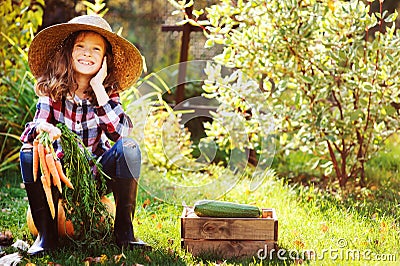 Happy farmer child girl sitting with autumn harvest in the garden Stock Photo