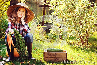 Happy farmer child girl sitting with autumn harvest in the garden Stock Photo