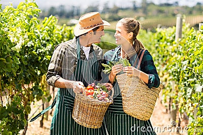 Happy farmer couple holding baskets of vegetables Stock Photo