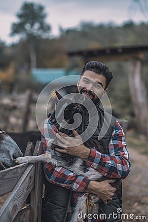 A happy farmer holding a cute goatling Stock Photo