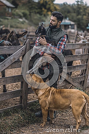 A happy farmer holding a cute goatling Stock Photo