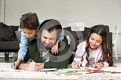 happy father with cute children lying on carpet and drawing with colored Stock Photo