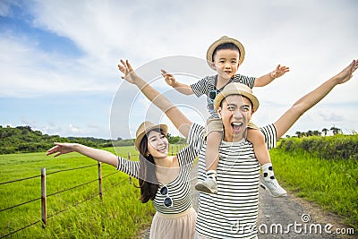 Happy father giving son piggyback ride on his shoulders and walking on country road Stock Photo