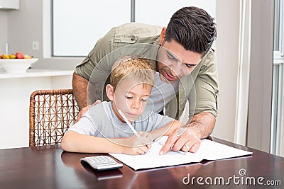 Happy father helping son with math homework at table Stock Photo