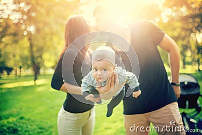 Happy father holds newborn baby on arm, kissing the mother of child. happy family in park, newborn kid and happiness Stock Photo