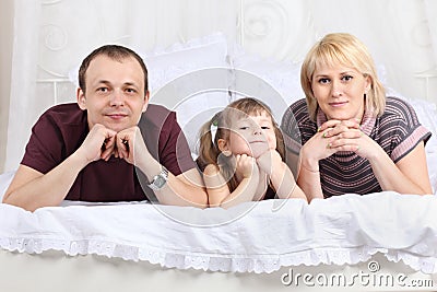 Happy father, little daughter and mother on white bed Stock Photo