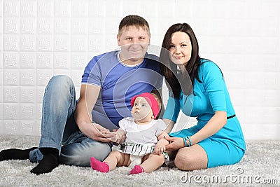 Happy father, mother and baby on grey carpet. Stock Photo