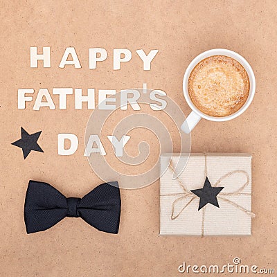 Happy Father`s Day Background. Cup of coffee, beautiful present and black bow tie on brown background flat lay. Fathers day. Stock Photo