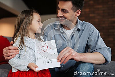 Happy father's day! Child daughter congratulates dad and gives him postcard. Daddy and girl, kissing, smiling and hugging Stock Photo