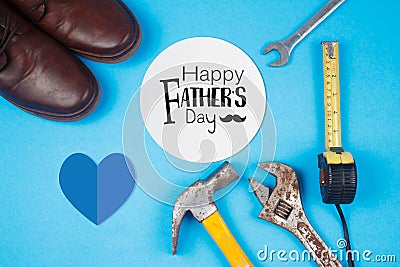 Happy Father`s Day text on card with old rusty tools and leather shoes on blue paper Stock Photo