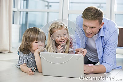 Happy father showing something to children on laptop at home Stock Photo