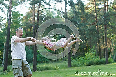 Happy father spinning around his daughter in green summer park outdoors Stock Photo