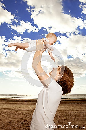 Happy father throws up baby boy against blue sky Stock Photo