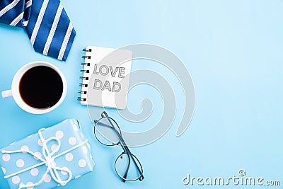 Happy fathers day concept. Top view of blue tie, beautiful gift box, coffee mug, glasses with LOVE DAD text on bright blue pastel Stock Photo