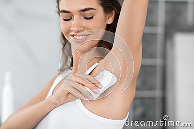 Happy Female Applying Antiperspirant Stick Underarms In Bathroom Indoor Stock Photo