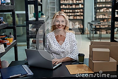 Happy female business owner or business woman sitting in her art studio or craft pottery shop with handmade ceramic Stock Photo