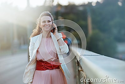 happy female in dress and jacket in city talking on phone Stock Photo