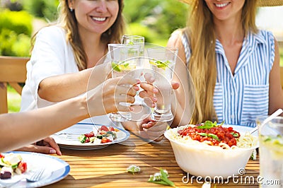 Happy female friends with glasses of lemonade at dining table in Stock Photo