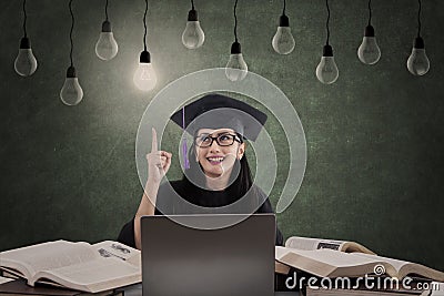 Happy female graduate has idea under lamps Stock Photo