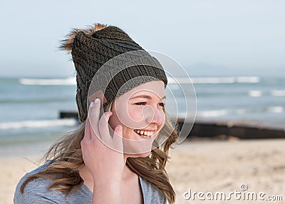 Happy female model wearing green knitted beanie with Bluetooth speakers Stock Photo
