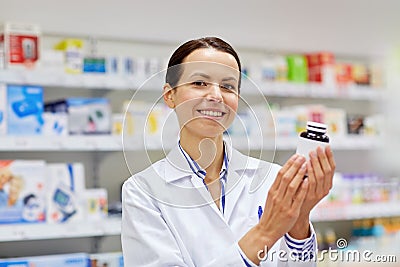 Happy female pharmacist with drug jar at pharmacy Stock Photo
