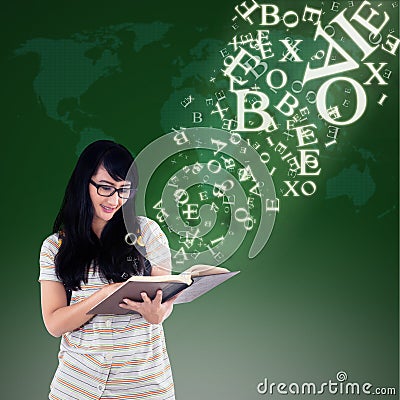 Happy female reading with alphabet letters coming out from book Stock Photo