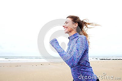 Happy female runner on beach with hair blowing Stock Photo