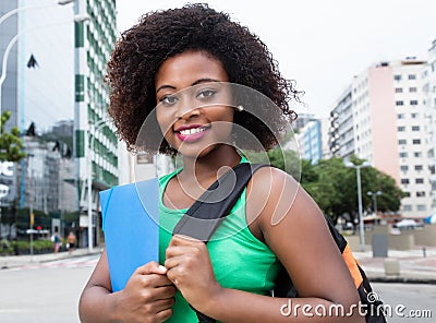 Happy female student from Africa in green shirt in city Stock Photo