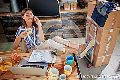 Happy female talking on her cell phone and drinking coffee with her legs on the table. casual, relaxed, break, pause Stock Photo