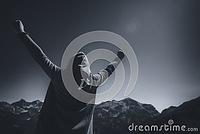 Happy female traveler with hands raised at mountain top Stock Photo