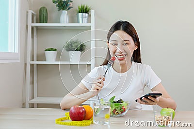 Happy females smiling eating salad vegetables fruit and using smartphone. Stock Photo