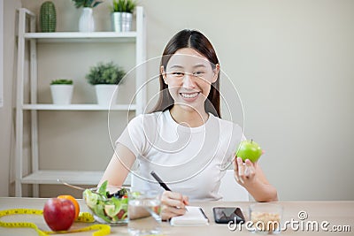 Happy females smiling holding apple take note of diet day weight counting calories. Stock Photo