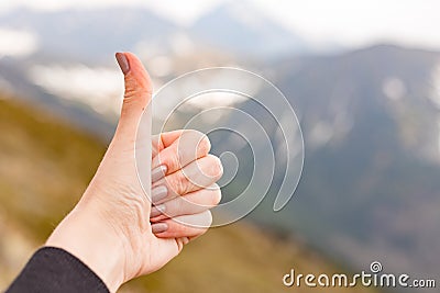 Happy fimale traveler showing thumb up in spring mountains, point of view shot Stock Photo