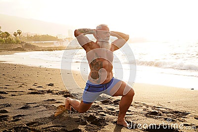 Happy fit senior man exercising on the beach during sunset time. In a healthy body healthy mind Stock Photo