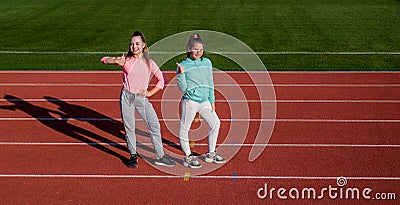 Happy fit girls show thumbs up standing on athletics track, physical fitness and sports promotion Stock Photo