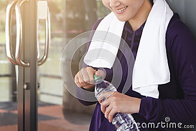 Happy fitness woman looking bottled water in her hand,refreshing after work out Stock Photo