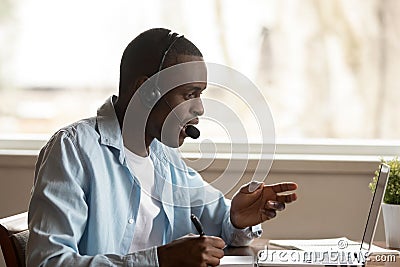 Happy focused african ethnic young guy attending online educational seminar. Stock Photo