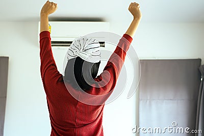 Happy fresh woman hand up and standing in front switching of the air conditioner Stock Photo