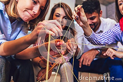 Friendly business team having fun at corporate training, funny teambuilding activity, playing spaghetti game Stock Photo