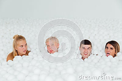 Happy Friendly family surrounded by white plastic balls in the dry pool. Stock Photo