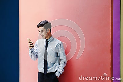 Happy and friendly young attractive Businessman use a Smart phone and holding morning coffee at colorful wall, Social communicate Stock Photo