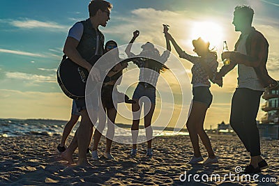Happy friends dancing on the beach. Men is playing guitar Stock Photo