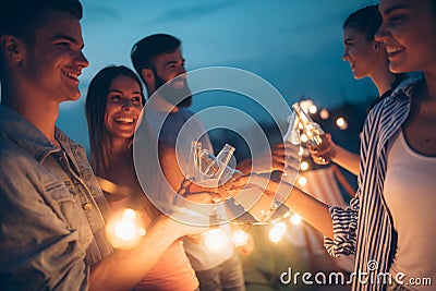 Happy friends with drinks toasting at rooftop party at night Stock Photo