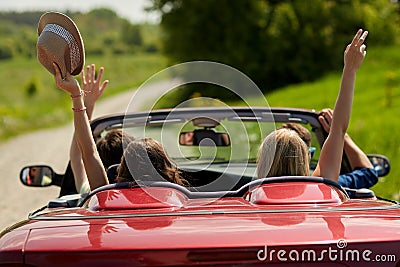 Happy friends driving in cabriolet car at country Stock Photo