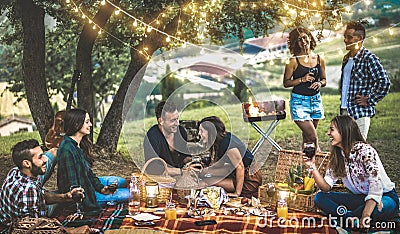 Happy friends having fun at vineyard after sunset - Young people millennial camping at open air picnic under bulb lights Stock Photo